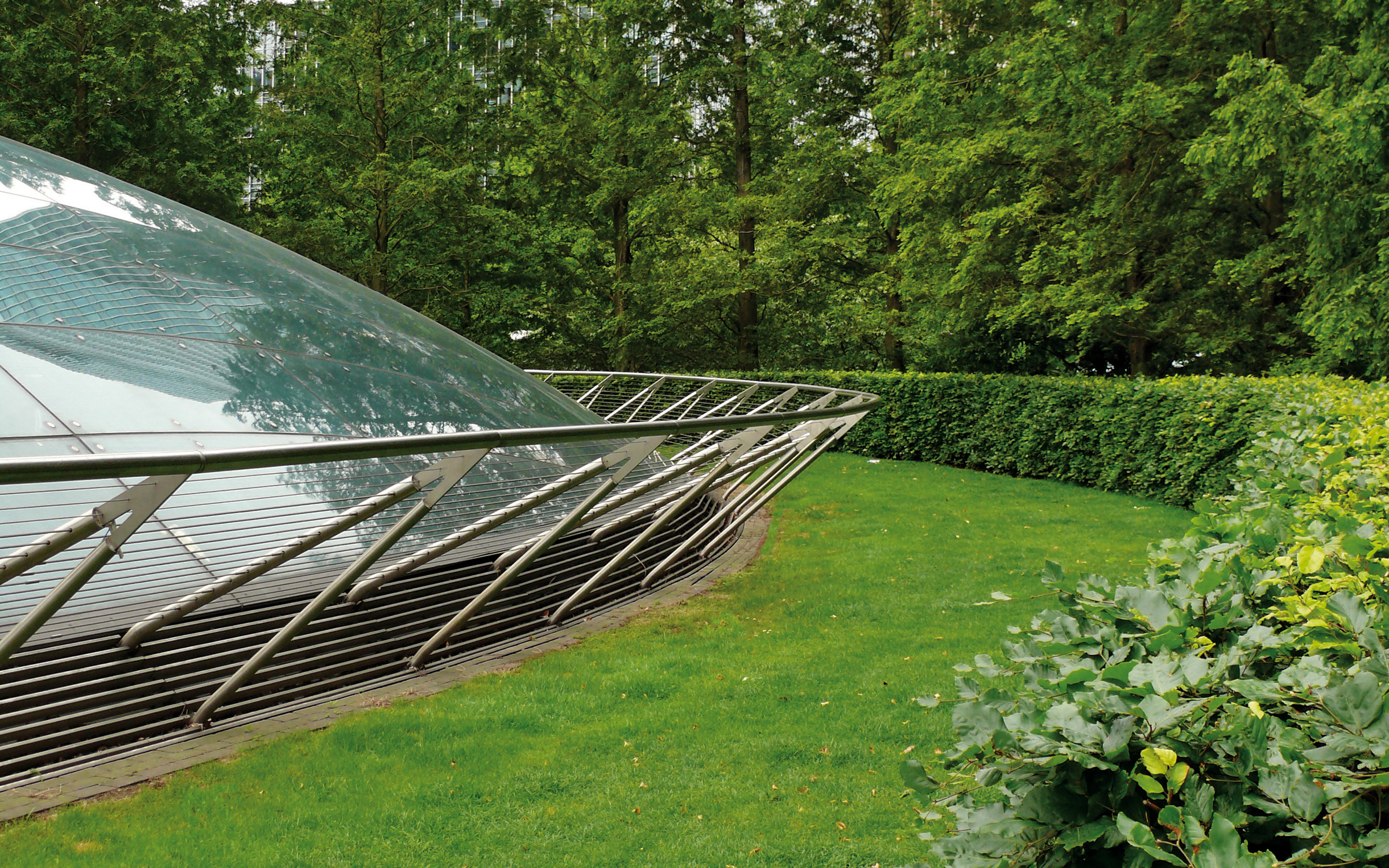Huge skylights provide the underground areas with natural light. Park with lawn, trees and huge skylights